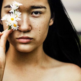 Visage d'une femme asiatique orné de pâquerettes.